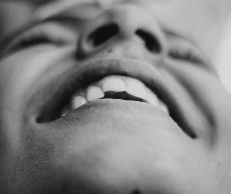 A black and white close-up of an open, laughing mouth