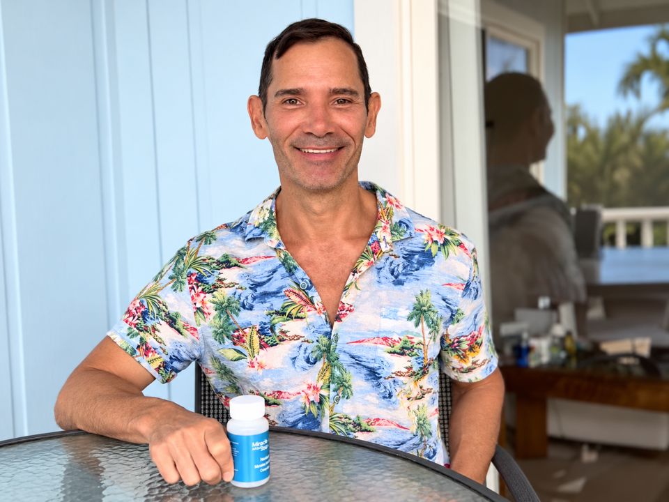 Cass P. at a patio table, holding a bottle of the capsules.