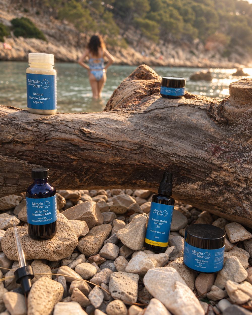 Miracle of the Sea capsules, oils and jars arranged on driftwood by the water.